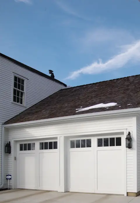 White carriage house garage door with decorative windows and classic detailing on a traditional home.