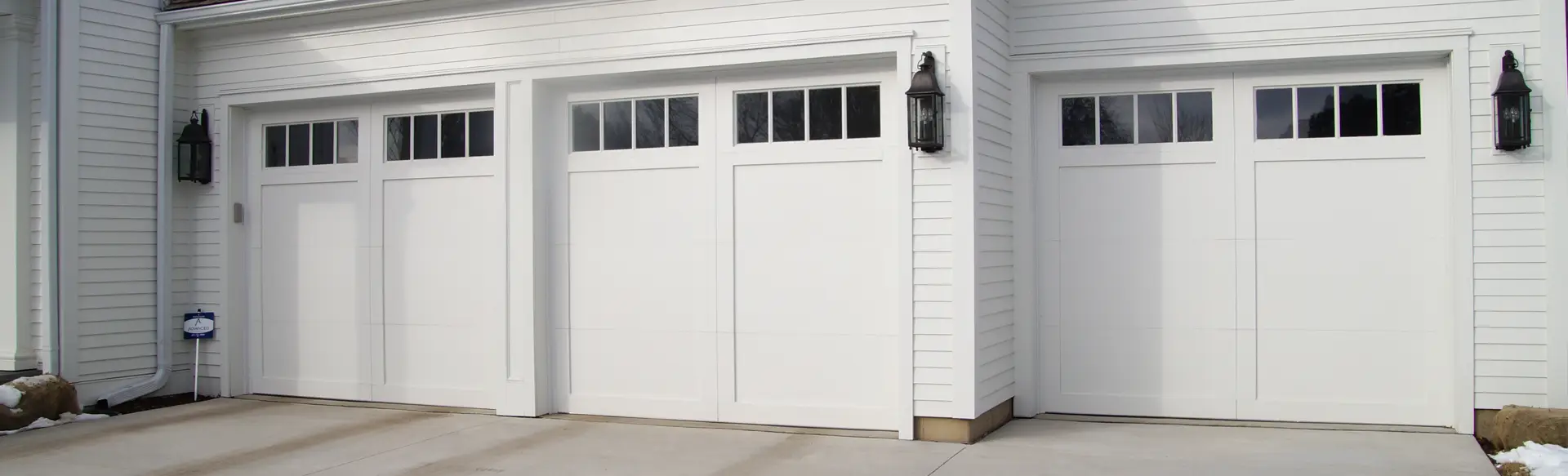 White carriage house garage door with decorative windows and classic detailing on a traditional home.