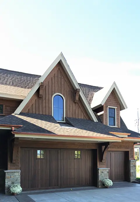 Dark stained wood garage door with a handcrafted design, creating a warm and elegant entrance.