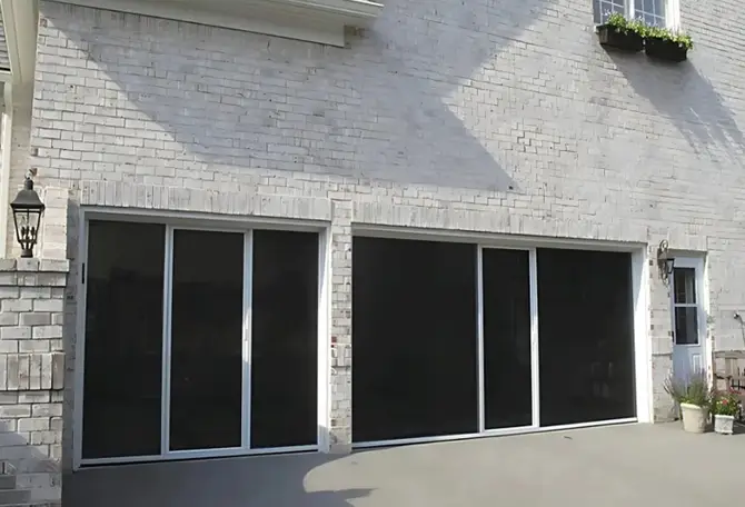 A white brick house with two garage screens