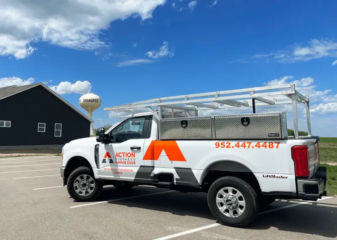 A white Action Overhead service truck is parked near stoplight in historic downtown Lakeville.