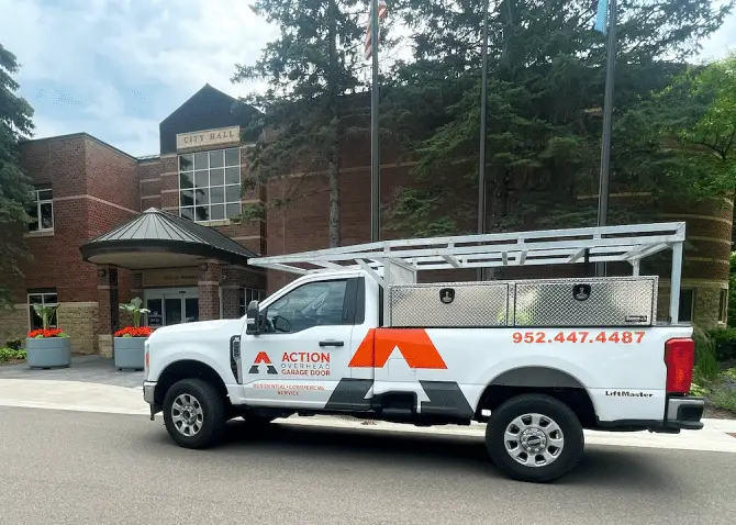An Action Overhead service truck is parked below the cream colored Andover water tower that rises into a deep blue sky.