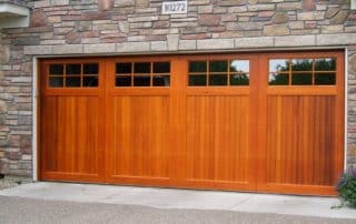 Solid wood, residential double car garage door with paneled glass on the top quarter of the door.