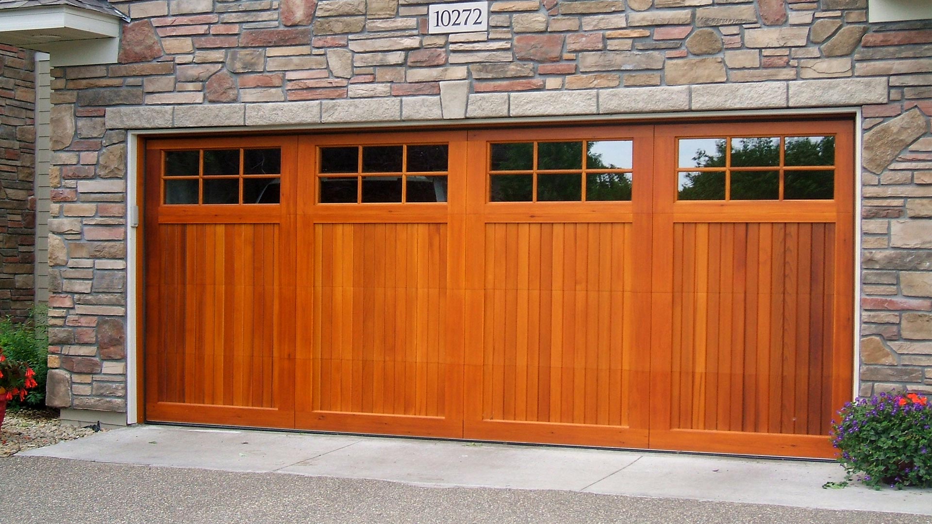 Solid wood, residential double car garage door with paneled glass on the top quarter of the door.